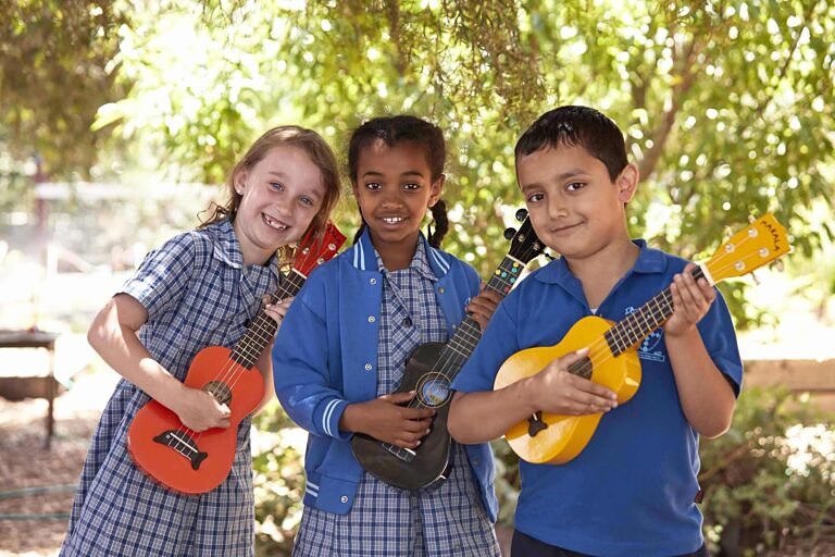 Three primary school students playing the ukulele together in their Song Room program.