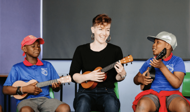 The Song Room Teaching Artist teaching two primary school students an arts learning music lesson in ukulele