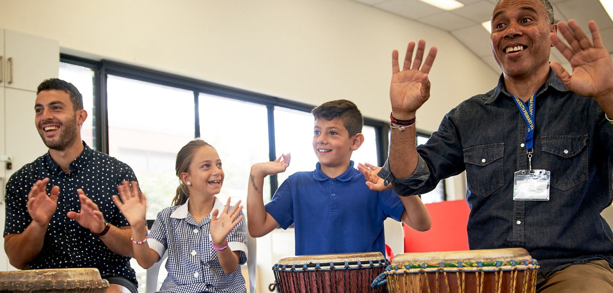two Song Room teaching artists teaching two primary school students an arts learning music lesson in African drums