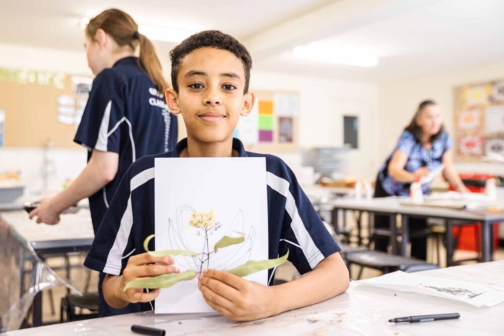 primary school student proudly showing class work on flowers