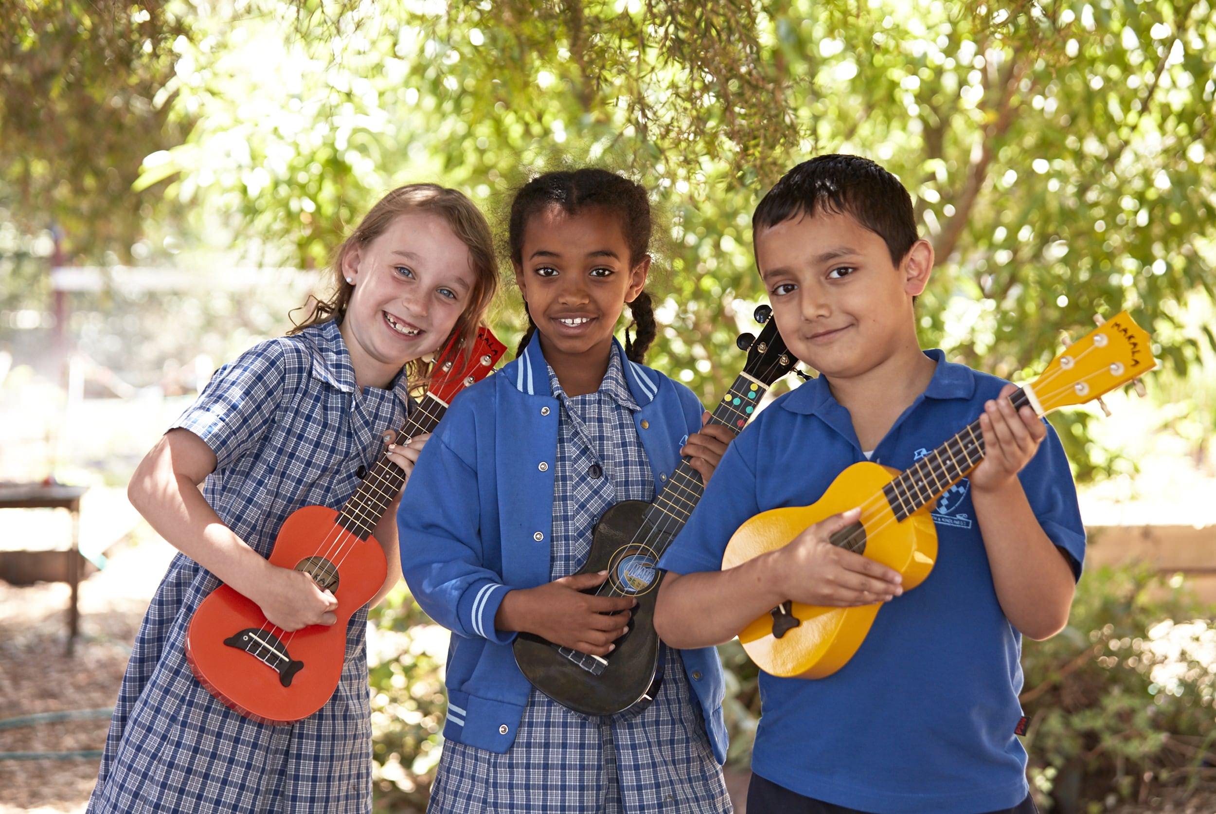 three primary school students enjoying an arts learning music education lesson on ukuleles