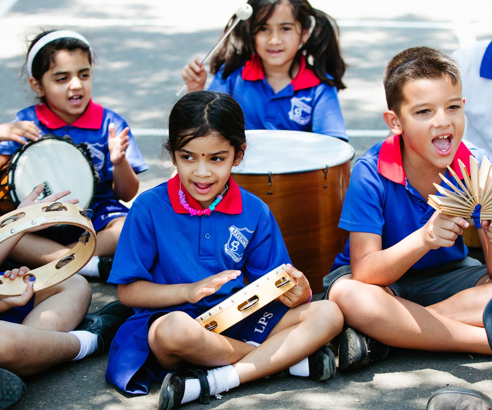 primary school students engaging in outdoor arts learning music lesson with percussion instruments
