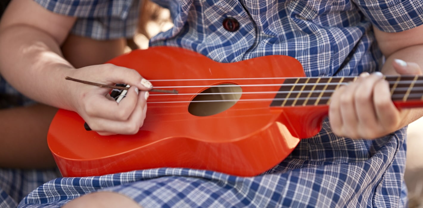 close up of primary school student playing ukulele