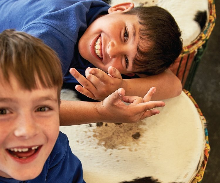 Two primary school students enjoying arts learning class on African drums