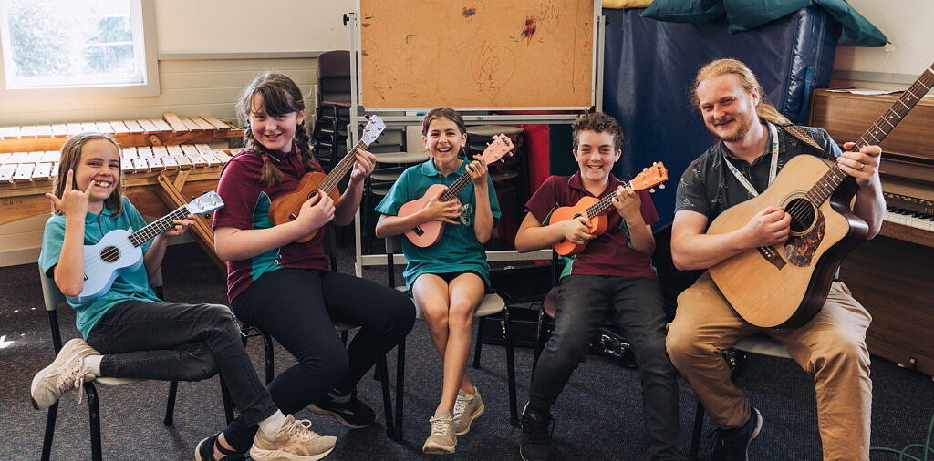 teaching artist delivering arts learning lesson to primary school students on guitars and ukulele