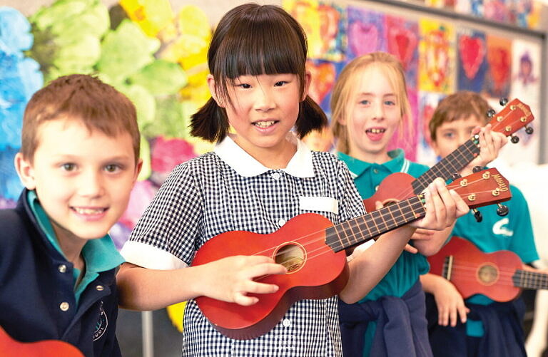 Primary school students enjoying arts and wellbeing program learning ukulele.