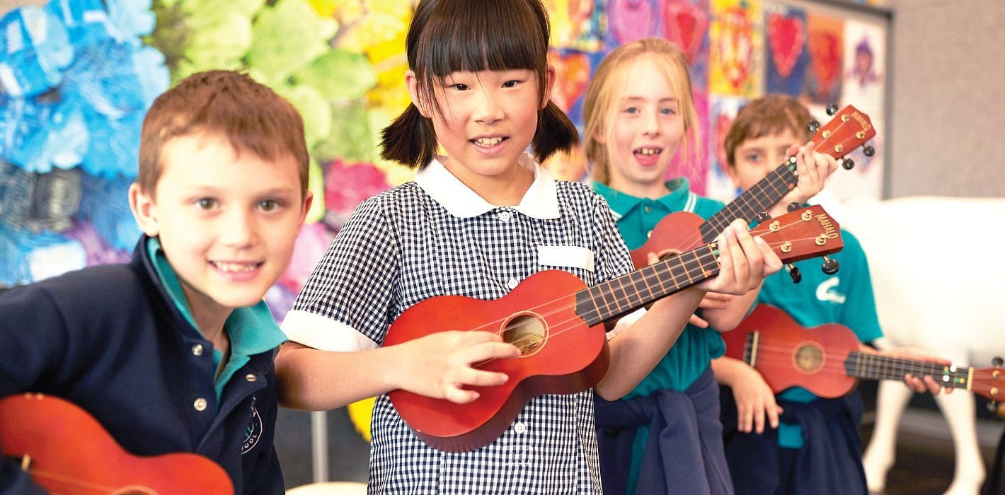 Primary school students enjoying arts and wellbeing program learning ukulele.