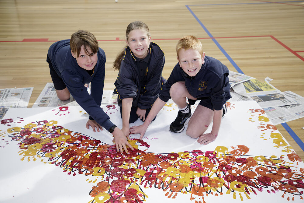 Young artists at The Song Room's Deadly Arts Community Celebration add their handprints to a collaborative painting, immersing themselves in First Nations culture through art and play.