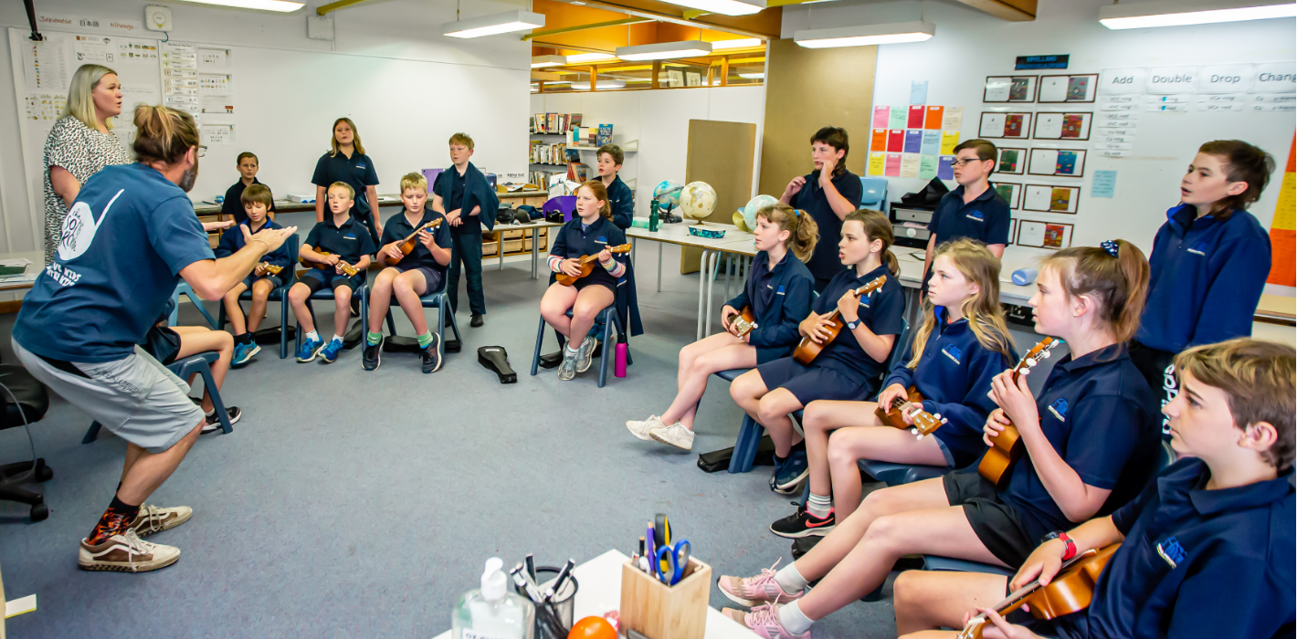 The Song Room Teaching Artist leading a professional learning session with a classroom teacher and primary students playing ukuleles to improve arts curriculum engagement.